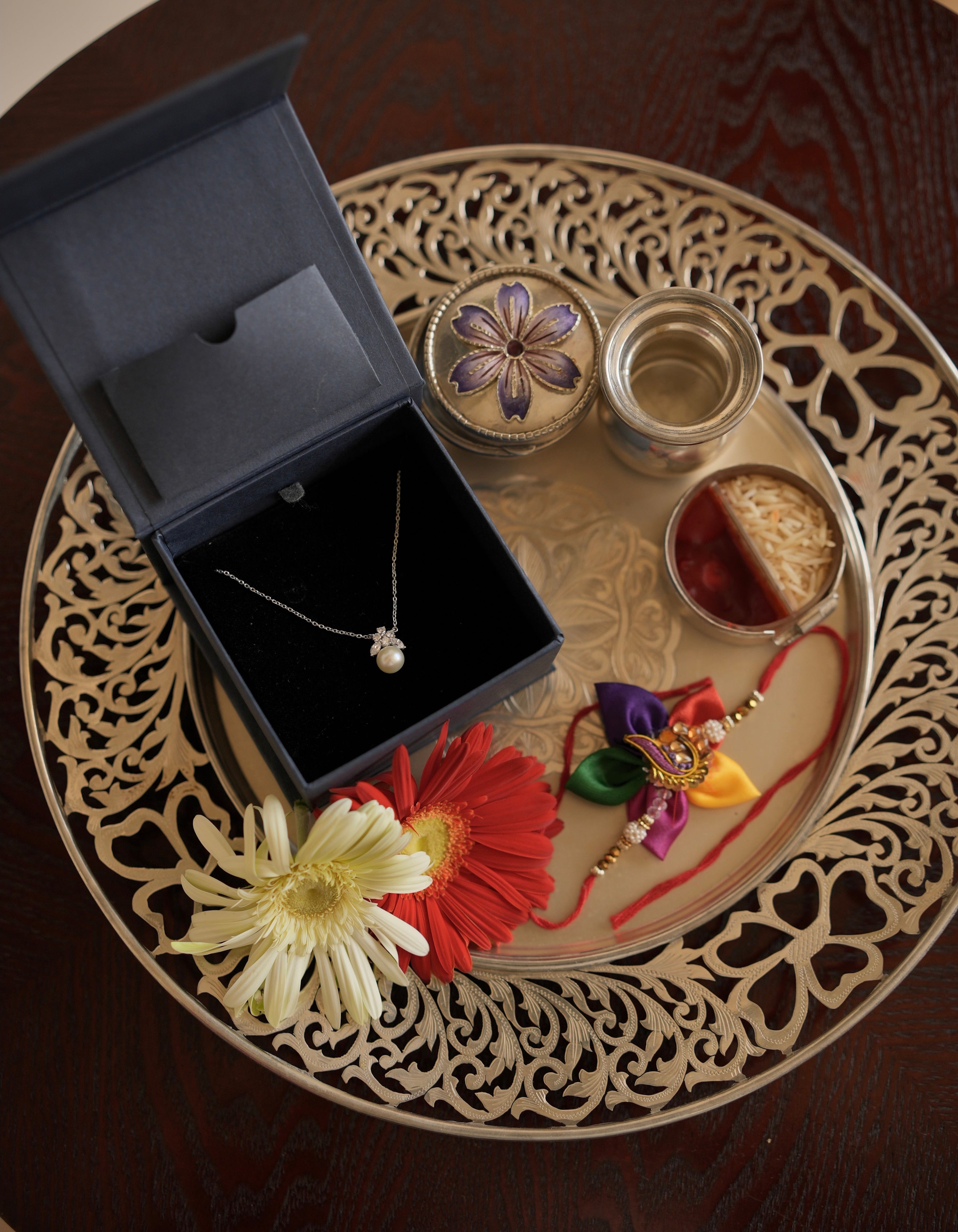Jewelry set with necklace, earrings, and decorative items on a decorative plate.